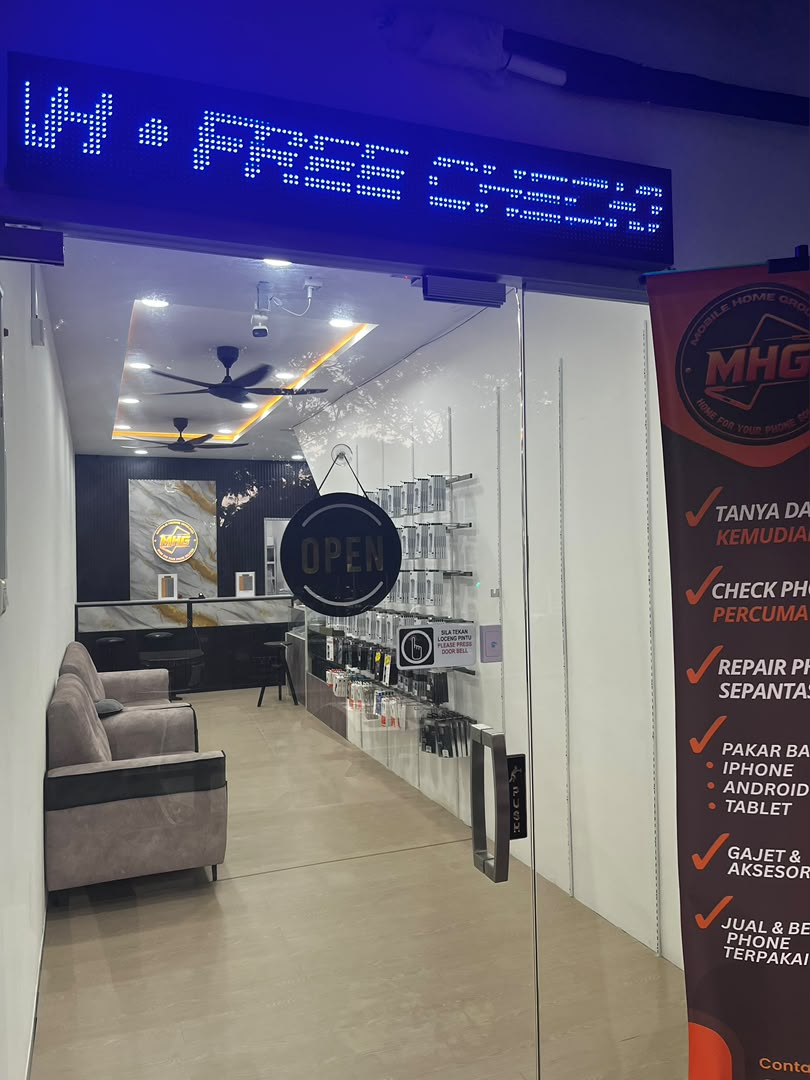 Pintu masuk kedai MHG waktu malam dengan papan tanda LED